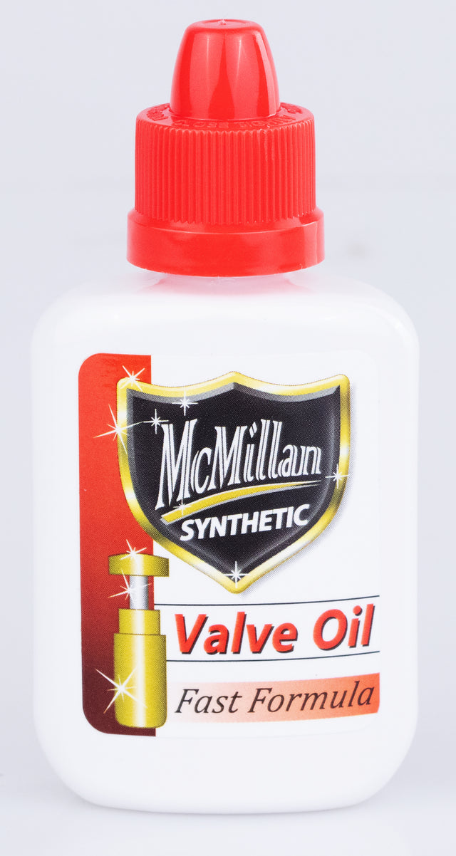 The image shows a bottle of McMillan Synthetic Valve Oil with a red cap and "Fast Formula" label. This specialized lubricant is used on brass instrument valves—such as trumpets and tubas—to ensure smooth, quick movement. Its synthetic formula offers long-lasting, non-gumming lubrication, while the thin consistency supports rapid valve action, essential for both students and professional players.