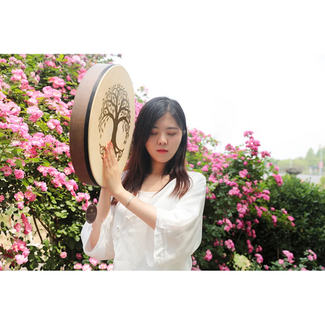 Woman playing a large wooden drum with floral background