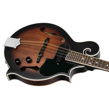 The image shows an electric mandolin with a hollow body and f-holes, featuring a sunburst finish and a classic scroll-shaped upper bout. It has a black pickguard, volume and tone knobs, metal tailpiece, and a fretted neck with dot inlays. The eight strings are arranged in four pairs. The instrument combines acoustic resonance with electric amplification, commonly used in bluegrass, folk, country, and rock music.