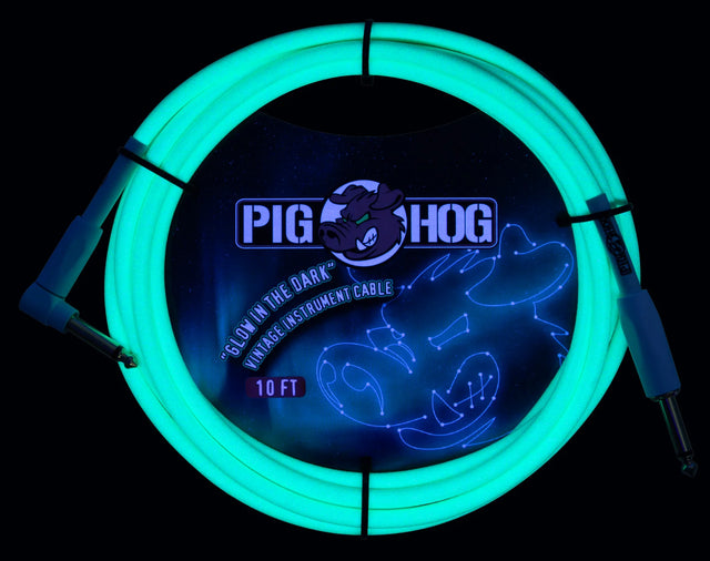 The image shows a coiled 10-foot Pig Hog "Glow in the Dark" vintage instrument cable with standard 1/4" plugs on both ends. The cable emits a bright cyan/turquoise light and features the Pig Hog logo with its pig mascot in the center. Designed for electric guitars and similar instruments, this novelty cable provides visibility and a unique look for musicians in dark performance settings.