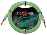 The image shows a coiled Pig Hog "Glow in the Dark" vintage 10-foot instrument cable with light green color and gold-plated 1/4" connectors with white housings, secured by black ties. The packaging features the Pig Hog logo with a red boar head and artwork of a glowing guitar on a dark background. This cable is used to connect electric guitars and other instruments to amplifiers or pedals.