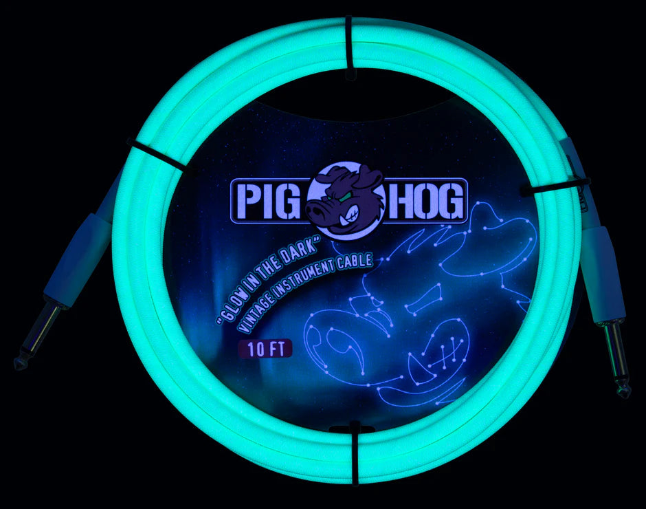 The image shows a coiled 10-foot Pig Hog instrument cable glowing bright cyan/turquoise against a dark background. It features glow-in-the-dark properties, standard 1/4" plugs on both ends, and the Pig Hog cartoon pig logo. Designed for electric guitars or basses, this vintage-style cable combines functionality with a unique glow effect, ideal for low-light stage performances.