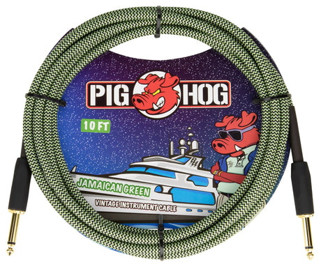 The image shows a 10-foot Pig Hog "Jamaican Green" vintage instrument cable with a green and black woven design, gold-plated 1/4" connectors, and the red pig mascot logo. The packaging features colorful space-themed artwork with the mascot on a yacht. This durable, professional-grade cable is used for connecting guitars, basses, keyboards, and other instruments to amplifiers or audio equipment.