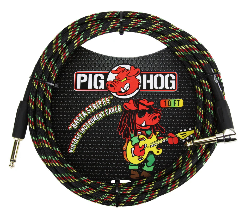 The image shows a Pig Hog "Rasta Stripes" 10-foot vintage instrument cable with a woven exterior in red, yellow, and green stripes on black. It has 1/4" connectors on both ends for electric instruments. The packaging displays the Pig Hog logo with a red pig mascot and a cartoon pig playing guitar in Rastafarian attire. The braided jacket offers durability, tangle resistance, and a distinctive look for professional musicians.