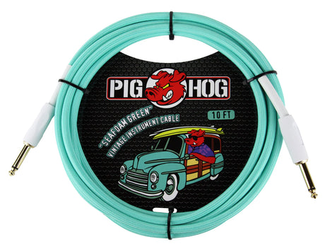 The image shows a 10-foot Pig Hog vintage instrument cable in seafoam green with gold-plated 1/4" connectors. It features Pig Hog’s distinctive packaging, including their red pig logo and a retro-style vintage car with surfboards, giving it a surf/vintage look. This guitar/instrument cable connects electric guitars, basses, or other instruments to amplifiers, combining functionality with a stylish, nostalgic design.