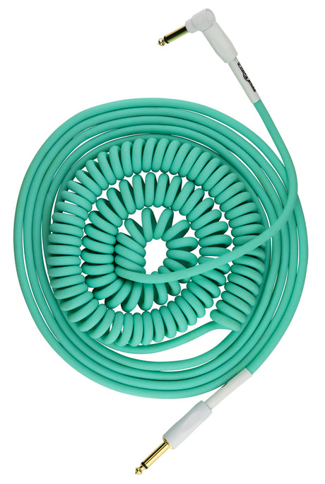 The image shows a coiled turquoise/mint green instrument cable with white connector housings and gold 1/4" phone plugs on both ends. Its spiral design allows stretch and retract for flexibility and compactness. Commonly used by guitarists and musicians, this professional-quality cable reduces stage clutter and tangling, combining a retro aesthetic with practical functionality ideal for studio or live performance.