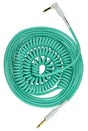 The image shows a coiled turquoise/mint green instrument cable with white connector housings and gold 1/4" phone plugs on both ends. Its spiral design allows stretch and retract for flexibility and compactness. Commonly used by guitarists and musicians, this professional-quality cable reduces stage clutter and tangling, combining a retro aesthetic with practical functionality ideal for studio or live performance.