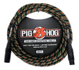 The image shows a Pig Hog Tour Grade 20-foot microphone cable with black XLR connectors. It has a colorful woven Rasta pattern exterior and features the red pig mascot logo. Marketed as "Built for the Road" with a lifetime guarantee, it comes in professional packaging with a black hexagonal background. This durable, tour-quality cable is designed for professional audio use.