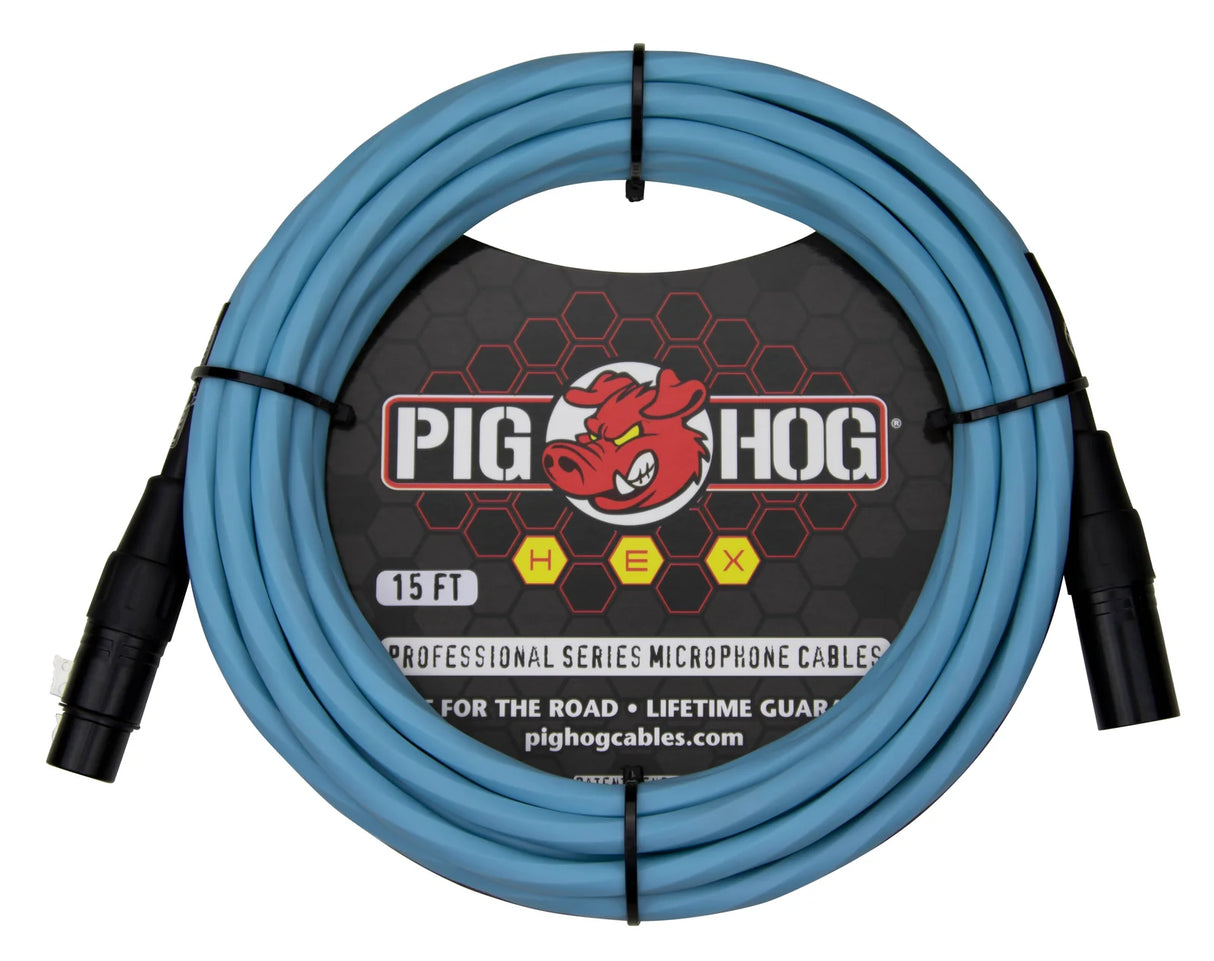 The image shows a 15-foot light blue Pig Hog HEX series professional microphone cable with black XLR connectors on both ends. It features the Pig Hog logo with a red cartoon pig, hexagonal pattern packaging, and is marketed "For the Road" with a lifetime guarantee. The coiled cable is designed for professional audio use, connecting microphones to mixers and audio equipment, emphasizing durability for live and studio settings.