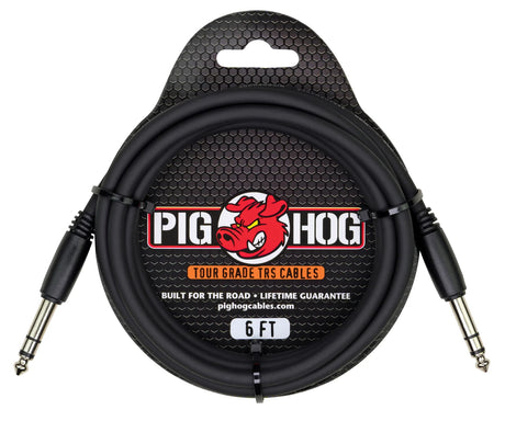 The image shows a Pig Hog 6-foot Tour Grade TRS audio cable with black 1/4" stereo/balanced connectors and a black cable. It features the red pig mascot logo and packaging with a hexagonal mesh design. Labeled "Built for the road" with a lifetime guarantee, it’s designed for durable, professional use in connecting instruments, mixers, and effects pedals.