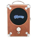 The image shows a Pignose portable guitar amplifier with a compact, suitcase-style brown/tan design, chrome corners, and a handle. It features a black speaker grille with a blue "Pignose" logo, a single control knob, a 1/4" input jack, and a built-in speaker. Popular since the 1970s, it’s favored by street performers and guitarists for its distinctive compressed tone and portability.