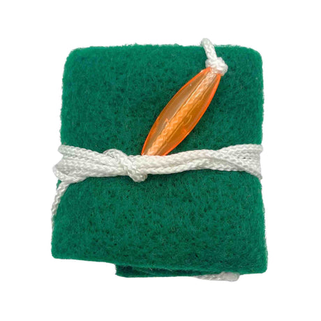 The image shows a green felt reed guard tied with white cord, holding an orange/amber woodwind reed, likely for clarinet, saxophone, or oboe. This protective case cushions and absorbs moisture to keep the delicate reed safe during transport and storage. Reed guards are essential for woodwind players to maintain reed condition and ensure sound quality.