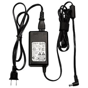The image shows a power adapter commonly used in the music industry to supply DC power to electronic instruments and audio gear. It features a wall plug, a power brick with certification labels, and an output cable with a connector. This adapter powers devices like keyboards, synthesizers, guitar pedals, audio interfaces, electronic drums, and digital pianos, making it essential for musicians using electronic equipment.