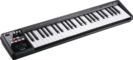 The image shows a Roland A-49 MIDI keyboard controller with 49 black and white piano keys. It has a sleek black casing and control buttons, including a modulation wheel, on the left side. This compact, portable device is used by musicians and producers to input notes and control music software. Roland is known for high-quality electronic instruments suitable for both studio and live performances.