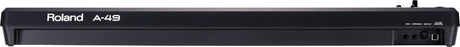 The image shows a Roland A-49 MIDI keyboard controller with 49 keys and a sleek black design. Visible features include the Roland branding on the front panel and rear connections like MIDI ports and USB. The compact, streamlined A-49 is part of Roland's portable A-Series, designed for music production, offering essential control for DAWs, software synths, and MIDI devices.