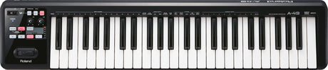 The image shows a Roland A-49 MIDI keyboard controller with 49 standard piano keys and a black casing. It features a control panel on the left with a power button, transport controls (play, stop, record), various parameter buttons, and a small display. Designed for music production, it controls software instruments and DAWs, making it popular for studio and live use due to its compact, portable design.