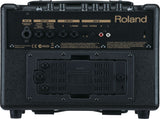 The image shows the back panel of a Roland guitar amplifier featuring DC power input, foot switch jack, left and right line outputs, and auxiliary input with level controls. It has multiple control knobs, a battery compartment with ventilation, and Roland branding. The compact, portable design supports battery operation, built-in effects, and loop control, making it suitable for practice, busking, or small performances.