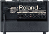 The image shows the back panel of a Roland guitar amplifier featuring a prominent logo, multiple input/output connections including LINE OUT (XLR), SUB WOOFER, AUX IN, 1/4" jacks, and footswitch ports. It has control knobs along the top, safety and certification labels, ventilation grilles, and a black textured finish. This modern amp offers extensive connectivity for live or studio use.
