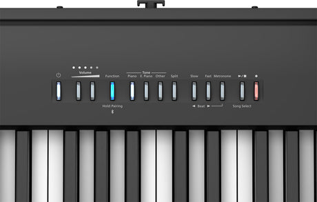 The image shows a digital piano keyboard with black and white keys and a control panel above. The panel features volume controls, tone and piano settings, split keyboard, tempo and metronome functions, beat and song selection, and other digital options. A blue-lit button and "Hold: Pairing" text indicate active Bluetooth connectivity for device pairing, highlighting its modern electronic features.
