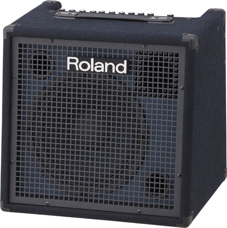 The image shows a Roland keyboard amplifier with a cube-style, compact design and dark blue textured exterior. It features a metal grille front with Roland branding, a top control panel with multiple knobs, a carrying handle, and reinforced corners. This professional, portable amp is designed for amplifying electronic keyboards and digital pianos, suitable for practice, rehearsal, and live performance.