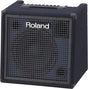 The image shows a Roland keyboard amplifier with a cube-style, compact design and dark blue textured exterior. It features a metal grille front with Roland branding, a top control panel with multiple knobs, a carrying handle, and reinforced corners. This professional, portable amp is designed for amplifying electronic keyboards and digital pianos, suitable for practice, rehearsal, and live performance.
