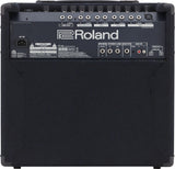 The image shows the back panel of a Roland keyboard amplifier or monitor speaker. It features multiple 1/4" inputs, XLR balanced output, stereo link, sub out, aux in, and a headphone jack. A row of control knobs is present for volume and EQ. There is a standard AC power inlet and the unit has a black textured finish with corner protectors, typical of professional audio gear.