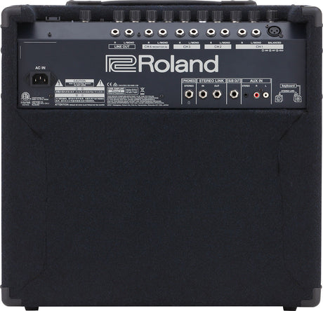 The image shows the back panel of a Roland keyboard amplifier or monitor speaker. It features multiple 1/4" inputs, XLR balanced output, stereo link, sub out, aux in, and a headphone jack. A row of control knobs is present for volume and EQ. There is a standard AC power inlet and the unit has a black textured finish with corner protectors, typical of professional audio gear.