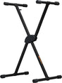 The image shows a black, adjustable X-style keyboard stand made of sturdy metal. It features height adjustment, adjustable upper arms with protective end caps, a central locking mechanism, and stable base feet. The stand, possibly branded, supports keyboards, synthesizers, or digital pianos, offering portability and stability for musicians during practice, recording, or live performances.