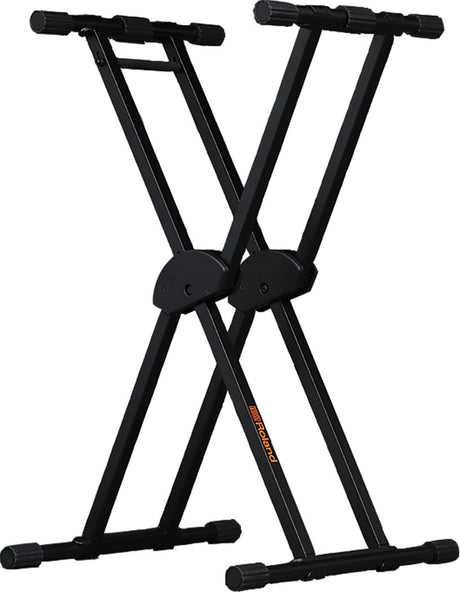 The image shows a black X-frame keyboard stand with double-braced legs for stability. It is made of metal, has adjustable height at pivot points, and foam padding on top arms to protect instruments. The stand is collapsible for easy transport and storage and features a "Roland" logo on one leg. This sturdy, portable stand is ideal for holding keyboards, synthesizers, or digital pianos during practice, studio work, or performances.