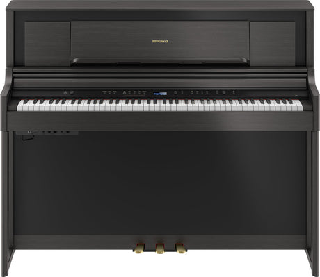 The image shows a Roland digital piano in a compact upright cabinet with a dark wood finish. It has a full 88-key weighted keyboard, a digital control panel with buttons and a small display, three pedals, and Roland branding on the music rack. This stylish, space-saving piano combines the feel of an acoustic piano with digital features like volume control and multiple voices, ideal for home use.