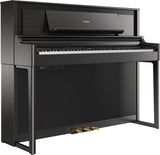 The image shows a Roland upright-style digital piano with a sleek dark wood finish. It features a full 88-key keyboard, three pedals, a digital control panel with buttons and a small display, a music rack, and the Roland logo on the top panel. Its modern, furniture-like design offers a space-efficient alternative to a grand piano while delivering an authentic piano playing experience with digital capabilities.