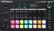 The image shows a Roland MC-101 Groovebox, a compact electronic music device combining a drum machine, sampler, and synthesizer. It features 16 velocity-sensitive RGB pads, 4 channel faders, multiple control knobs, a digital display, transport controls, and various editing buttons. Designed for beatmaking and live performance, it offers a portable, all-in-one solution favored by electronic music producers.