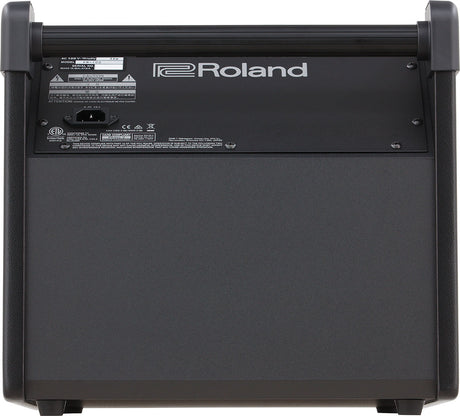 The image shows the back panel of a Roland musical instrument or amplifier with the "Roland" logo prominently displayed. It features a sturdy design with a carrying handle and corner protectors. A specification label with technical info, safety warnings, and regulatory markings, including a CE mark, is visible. The panel includes a power inlet (marked "A"). This likely belongs to a professional keyboard or guitar amplifier from Roland’s product line.