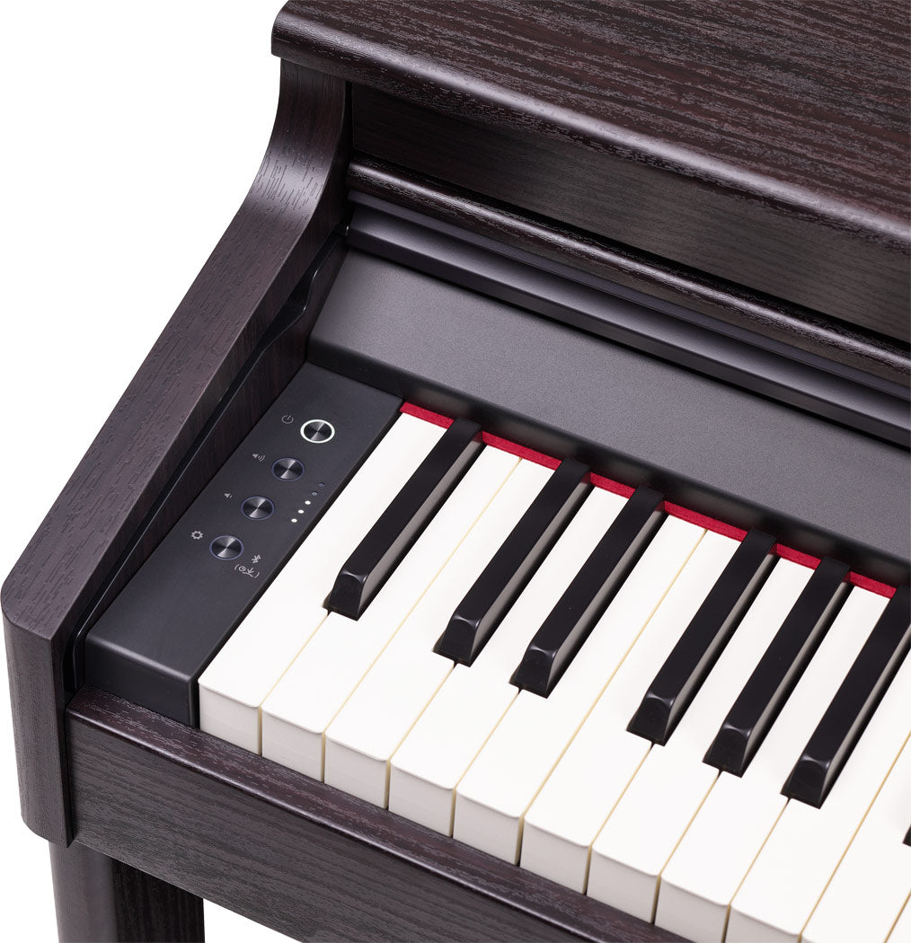 The image shows a digital piano with a traditional white and black keyboard housed in a dark wood grain cabinet, giving it an elegant, furniture-like appearance. It features a control panel with buttons on the left side, including power and volume controls. The keys appear weighted or semi-weighted, and the design suggests it’s a home digital piano rather than a portable keyboard.