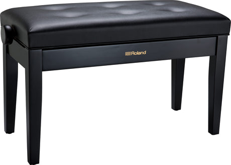 The image shows a Roland piano bench with a sleek black finish and a padded, button-tufted vinyl seat. It has four sturdy wooden legs and features the Roland logo in gold on the front panel. This professional-quality, adjustable bench is designed for comfortable seating during piano and keyboard practice or performance. Roland is a well-known brand in digital pianos and electronic instruments.