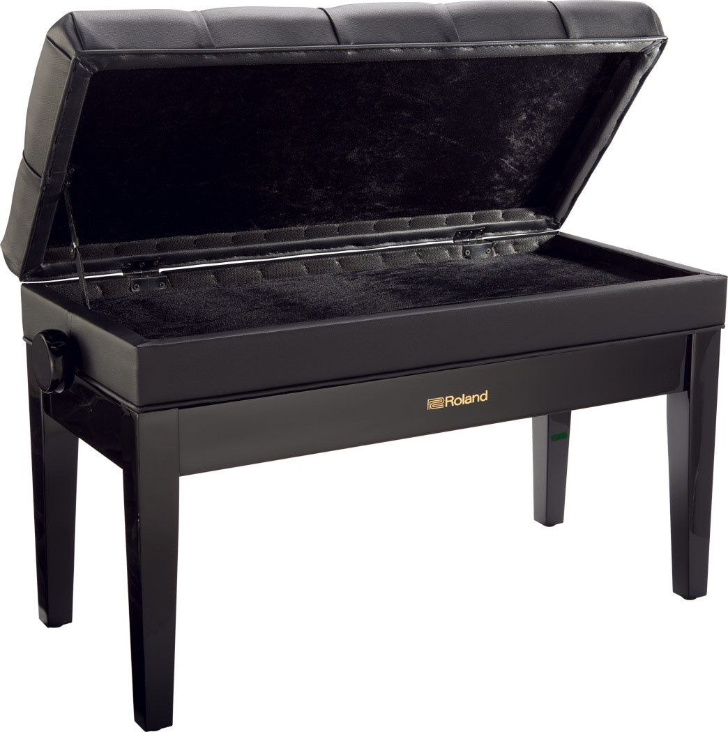 The image shows a Roland piano bench with a sleek black finish, padded tufted seat, adjustable height knob, and an open storage compartment lined with black fabric beneath the seat. It has four sturdy legs and the Roland logo on the front. This bench offers comfortable seating and convenient storage for sheet music and accessories, making it a popular choice for piano and keyboard players.