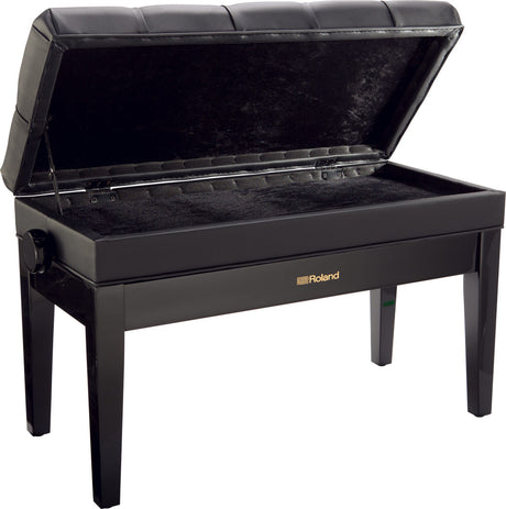The image shows a Roland piano bench with a sleek black finish, padded tufted seat, adjustable height knob, and an open storage compartment lined with black fabric beneath the seat. It has four sturdy legs and the Roland logo on the front. This bench offers comfortable seating and convenient storage for sheet music and accessories, making it a popular choice for piano and keyboard players.