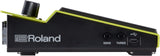 The image shows a Roland electronic drum trigger pad with a sleek black design and bright green/yellow trim. Visible features include the Roland logo, two control knobs labeled "SENS" and "THRES" for sensitivity and threshold adjustments, a USB port, and a trigger input jack. Its wedge shape is typical for drum modules, used by drummers to trigger electronic sounds with customizable response settings.