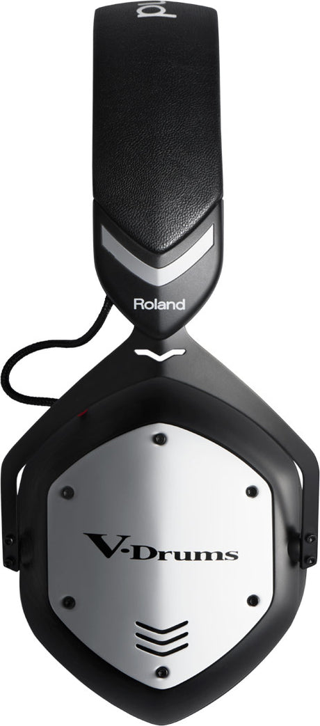 The image shows Roland V-Drums professional over-ear headphones in black and silver, designed for electronic drum kits. Featuring the "V-Drums" label on the ear cup, they have padded ear cushions, a closed-back design for sound isolation, and robust construction. These headphones provide clear, accurate sound for drummers during practice, performance, or recording without disturbing others.