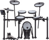 The image shows a Roland electronic drum kit featuring multiple white drum pads, electronic cymbal pads including crash and ride, black metal hardware, a control module with digital display, a large kick drum pad with pedal, and electronic hi-hat cymbals with pedal. This modern digital set simulates acoustic drums, ideal for quiet practice, recording, and performance with volume control and sound versatility.