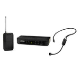 The image shows a Shure wireless microphone system with three main components: a black wireless receiver with a digital display (center), a compact bodypack transmitter with antenna (left), and a lightweight headset microphone with a flexible boom (right). This system is used by musicians and performers for hands-free, cable-free amplification during live shows and recordings.