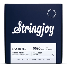The image shows a package of Stringjoy "Signatures" 7-string electric guitar strings, gauge 10-60, nickel wound with balanced light tension. The deep navy box features white lettering, an elegant script logo, and "Made in Nashville, N.L." marking. This premium set is designed for extended range guitars, offering comfortable playability and tone across all seven strings.