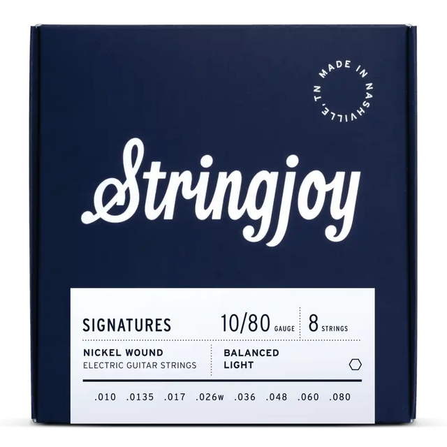 The image shows a navy blue package of Stringjoy "Signatures" 8-string electric guitar strings. The set features balanced light, nickel wound strings with gauges .010 to .080. The minimalist box includes white text and a "Made in Nashville, TN" logo. Designed for extended range guitars, it supports low tunings with a heavy .080 bass string.