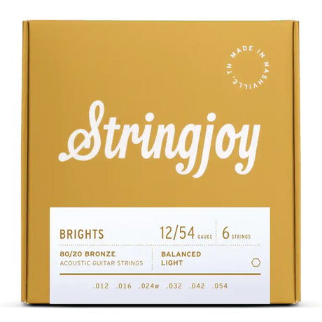 The image shows a package of Stringjoy "Brights" acoustic guitar strings. The light gauge 12-54 set is made of 80/20 bronze with six strings (.012 to .054). The packaging features a golden-yellow box with white script logo, a white info panel, and a "Made in Nashville" badge, highlighting a premium, professional presentation.