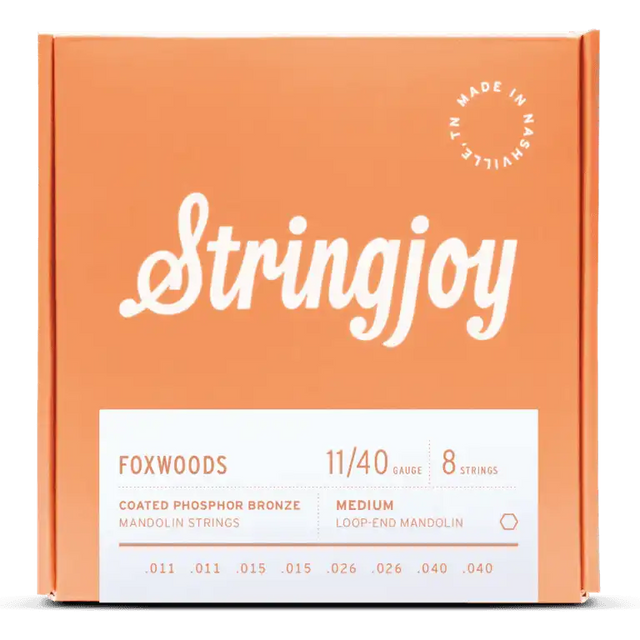 The image shows a package of Stringjoy Foxwoods Coated Phosphor Bronze mandolin strings in medium gauge 11/40. It contains 8 medium loop-end strings (.011, .011, .015, .015, .026, .026, .040, .040) in a coral-orange box with white script branding. A "Made in Nashville" logo appears in the top right, and product details are on a white label at the bottom. The coated strings offer enhanced tone and durability.