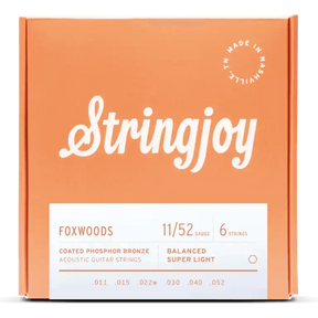The image shows a package of Stringjoy Foxwoods coated phosphor bronze acoustic guitar strings. The orange/coral box features a script-style logo, a "Made in Nashville" badge, and a white label listing specs. This 6-string set is Balanced Super Light gauge 11-52 (.011, .015, .022w, .030, .040, .052), offering warm tone and corrosion resistance.
