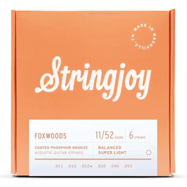 The image shows a package of Stringjoy Foxwoods coated phosphor bronze acoustic guitar strings. The orange/coral box features a script-style logo, a "Made in Nashville" badge, and a white label listing specs. This 6-string set is Balanced Super Light gauge 11-52 (.011, .015, .022w, .030, .040, .052), offering warm tone and corrosion resistance.