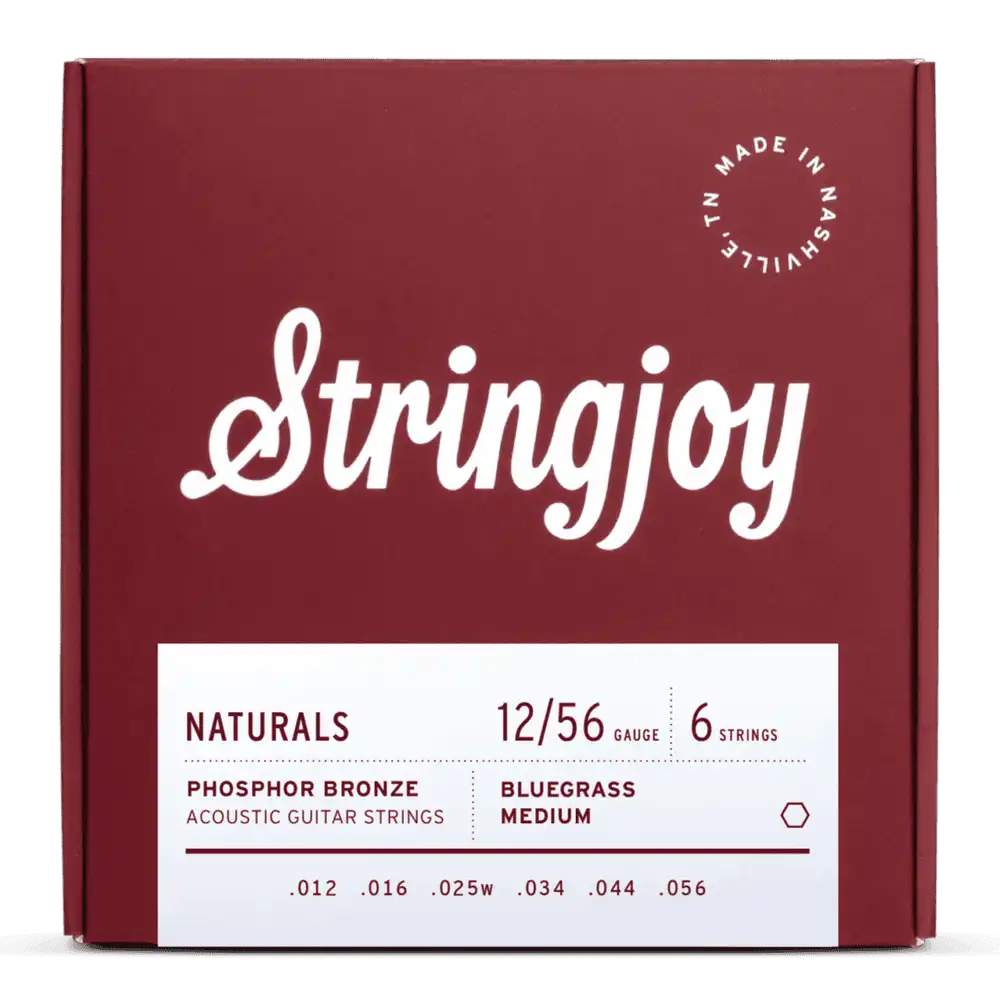 The image shows a package of Stringjoy acoustic guitar strings from the "Naturals" line. It features a burgundy box with white script, a "Made in Nashville, TN" stamp, and a white label with specs. The set includes 6 phosphor bronze strings, gauge 12/56 (medium), with tensions labeled "Bluegrass Medium," designed for warm tone and balanced playability.