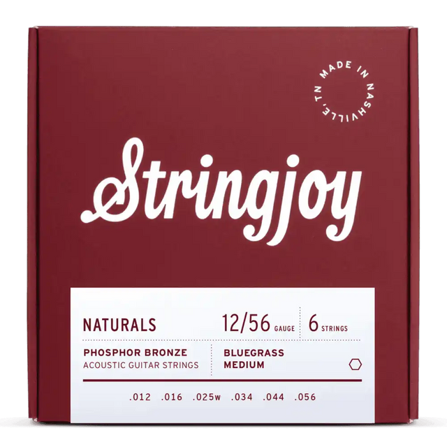 The image shows a package of Stringjoy acoustic guitar strings from the "Naturals" line. It features a burgundy box with white script, a "Made in Nashville, TN" stamp, and a white label with specs. The set includes 6 phosphor bronze strings, gauge 12/56 (medium), with tensions labeled "Bluegrass Medium," designed for warm tone and balanced playability.