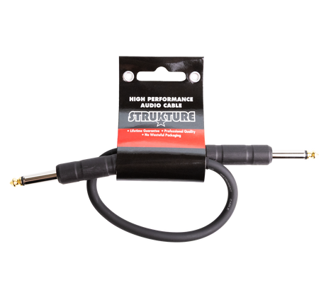 The image shows a STRUKTURE high-performance audio patch cable with gold-plated 1/4" TS/TRS connectors. It is a short, black professional-grade cable, likely 6-12 inches long, designed for connecting effects pedals or instruments to amplifiers. The cable features a lifetime guarantee, professional quality, and eco-friendly packaging, appealing to musicians seeking reliable, low-noise audio connections.